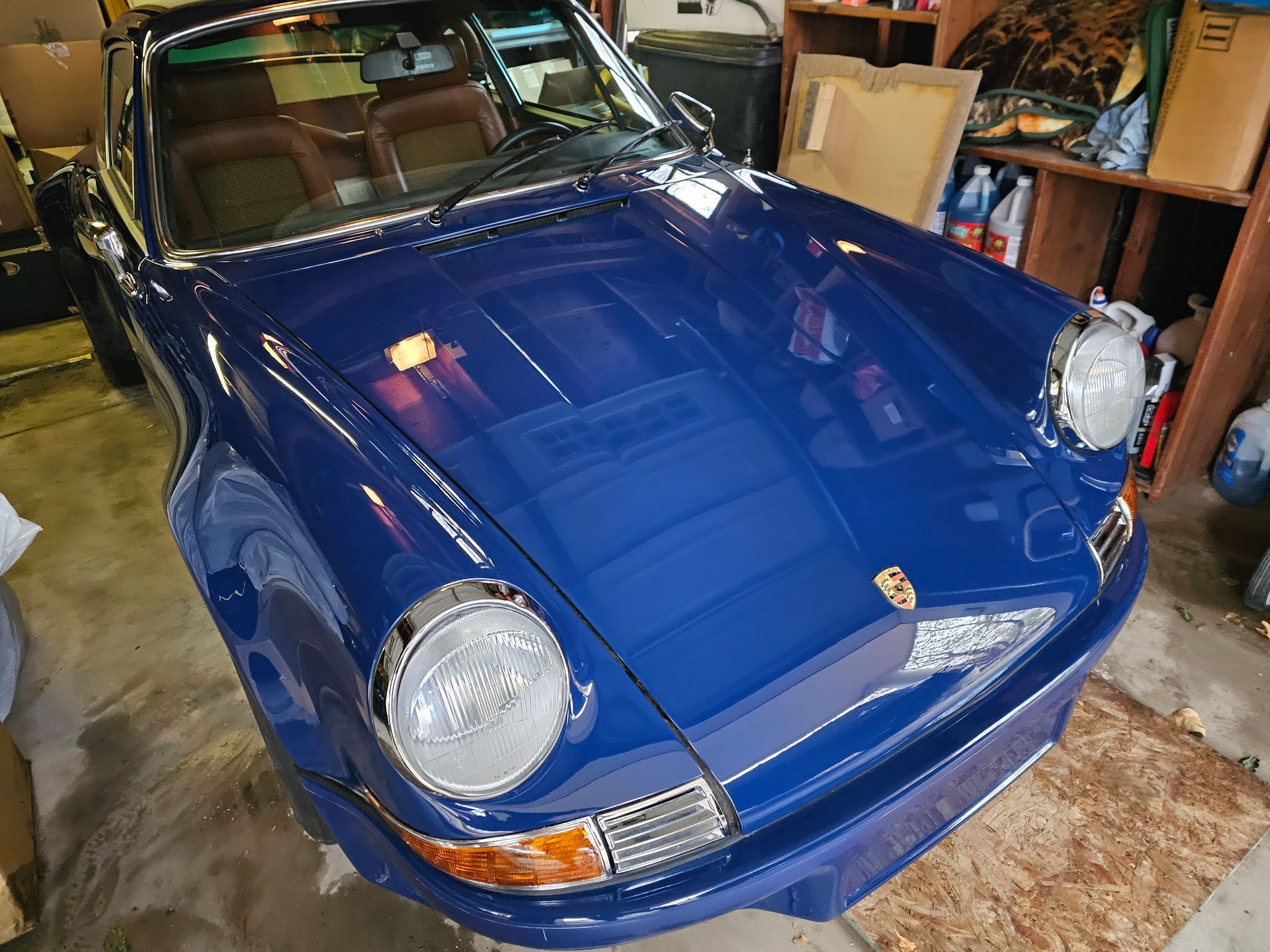 Blue Porsche 911 parked in a garage, viewed from the front-left side.