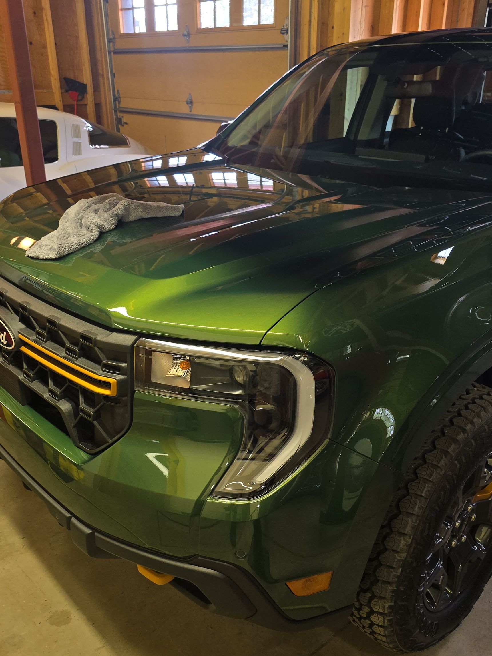 Green pickup truck with snow on the hood parked inside a garage