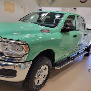 Mint green pickup truck in a showroom, front-left view, with chrome accents and black side steps