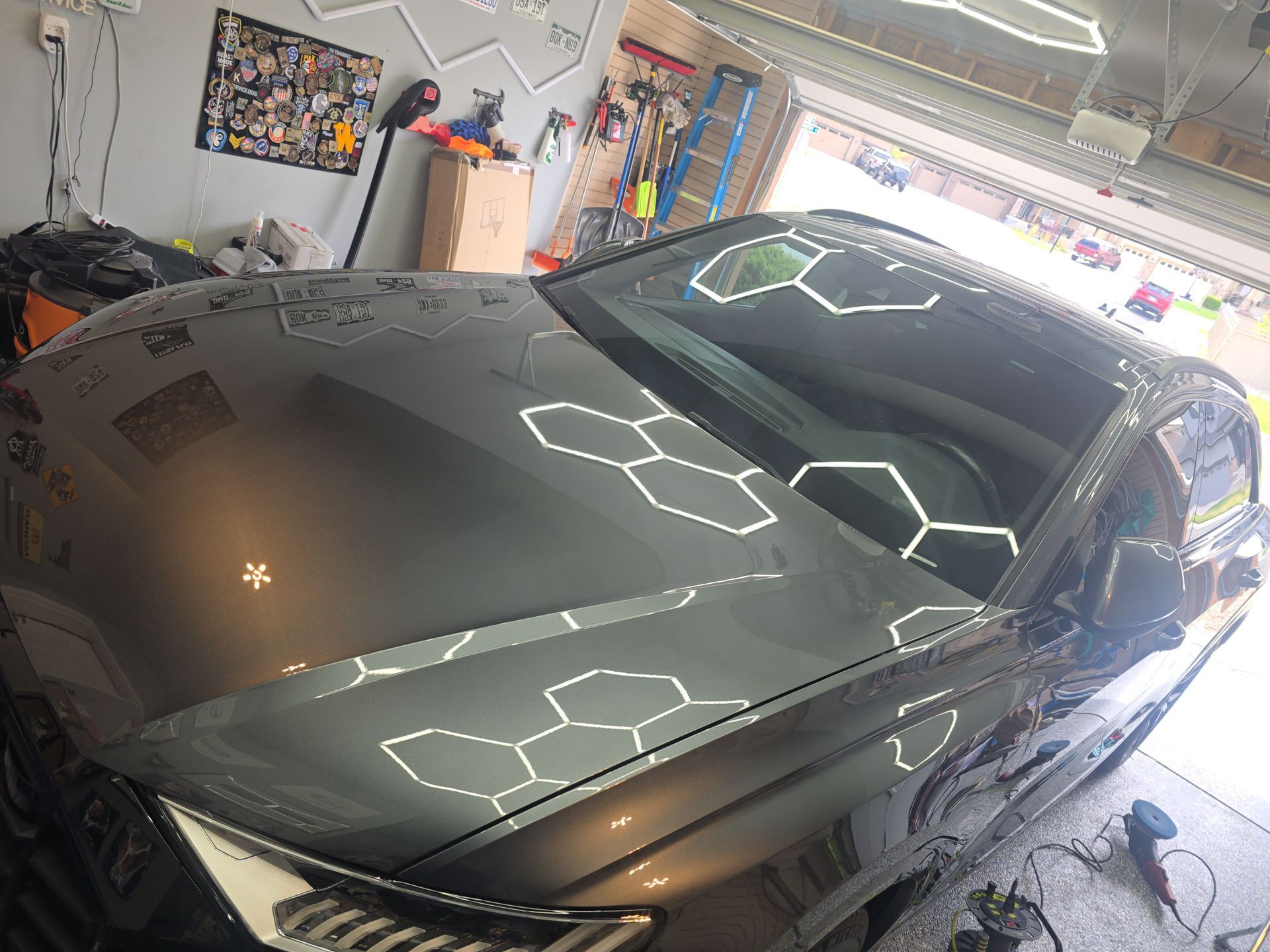 Black sports car in a garage with reflections on its hood and windshield