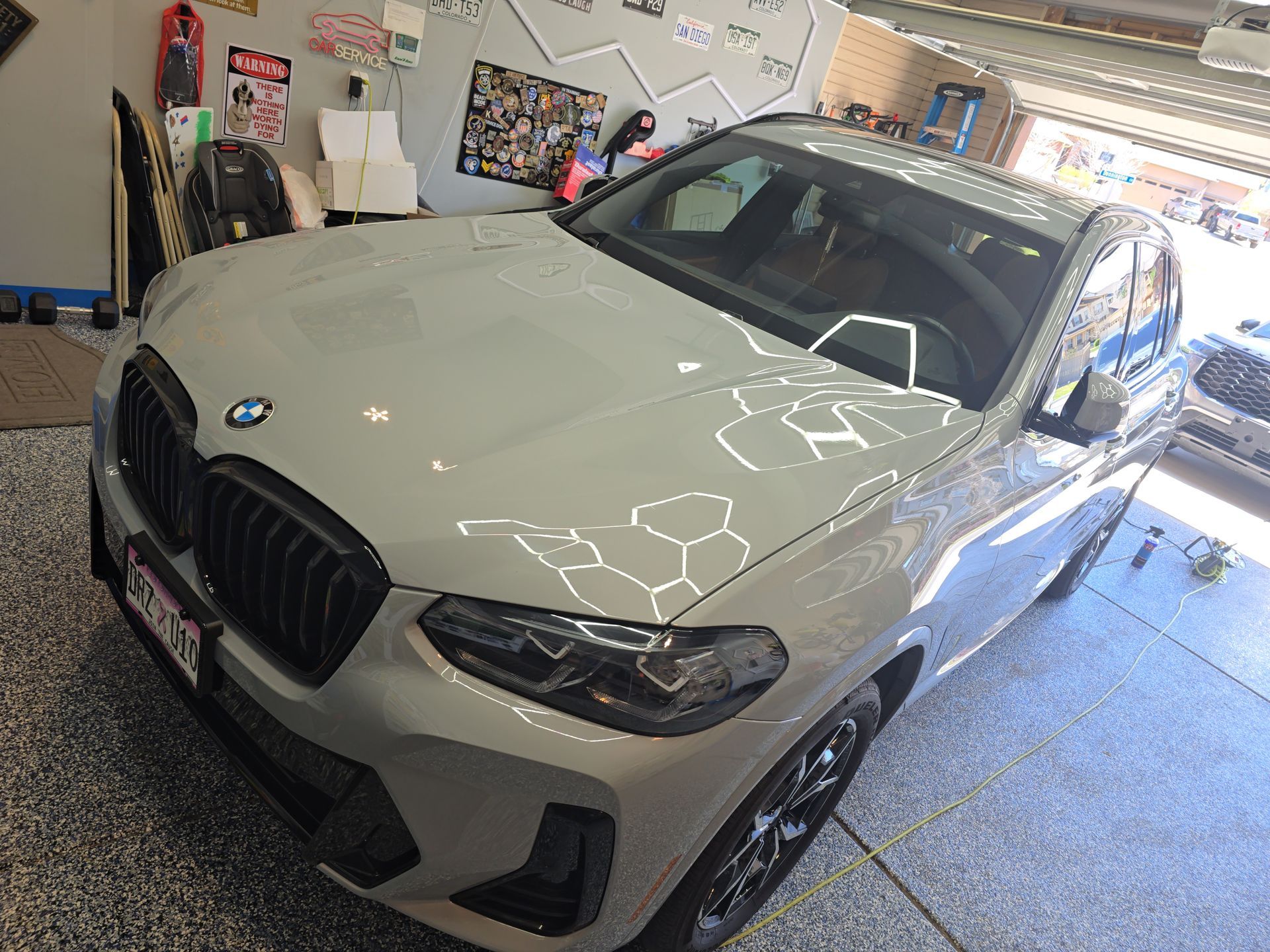 White BMW sedan parked in a garage with bright reflections on the hood and windshield