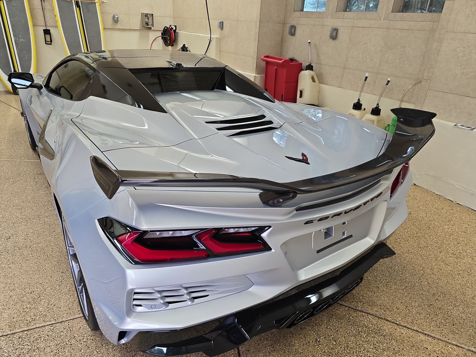 Silver sports car with a large rear spoiler parked indoors in a garage-like setting