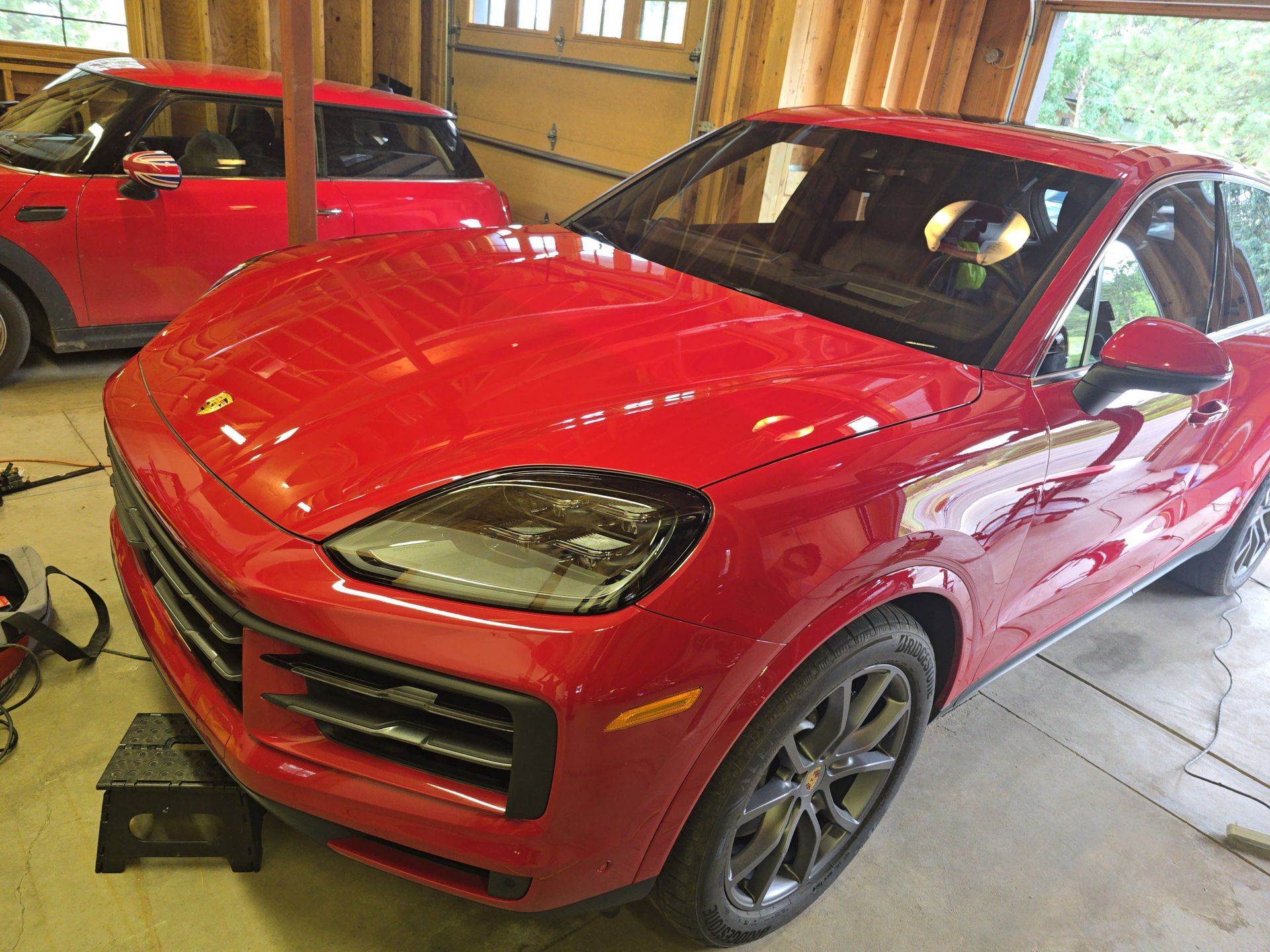 Red SUV parked indoors beside a red sports car in a garage