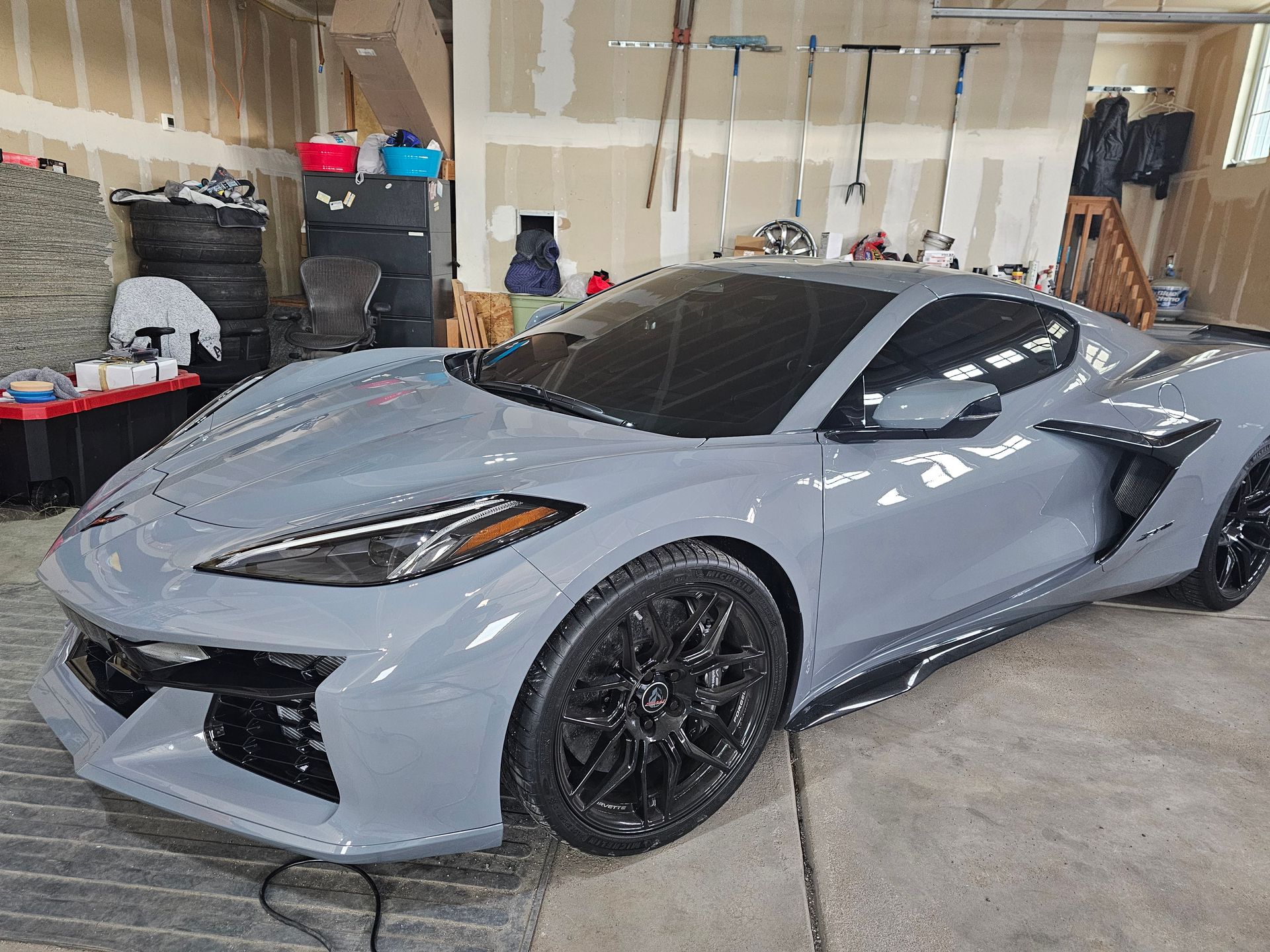 Gray sports car parked inside a garage with black wheels and tinted windows