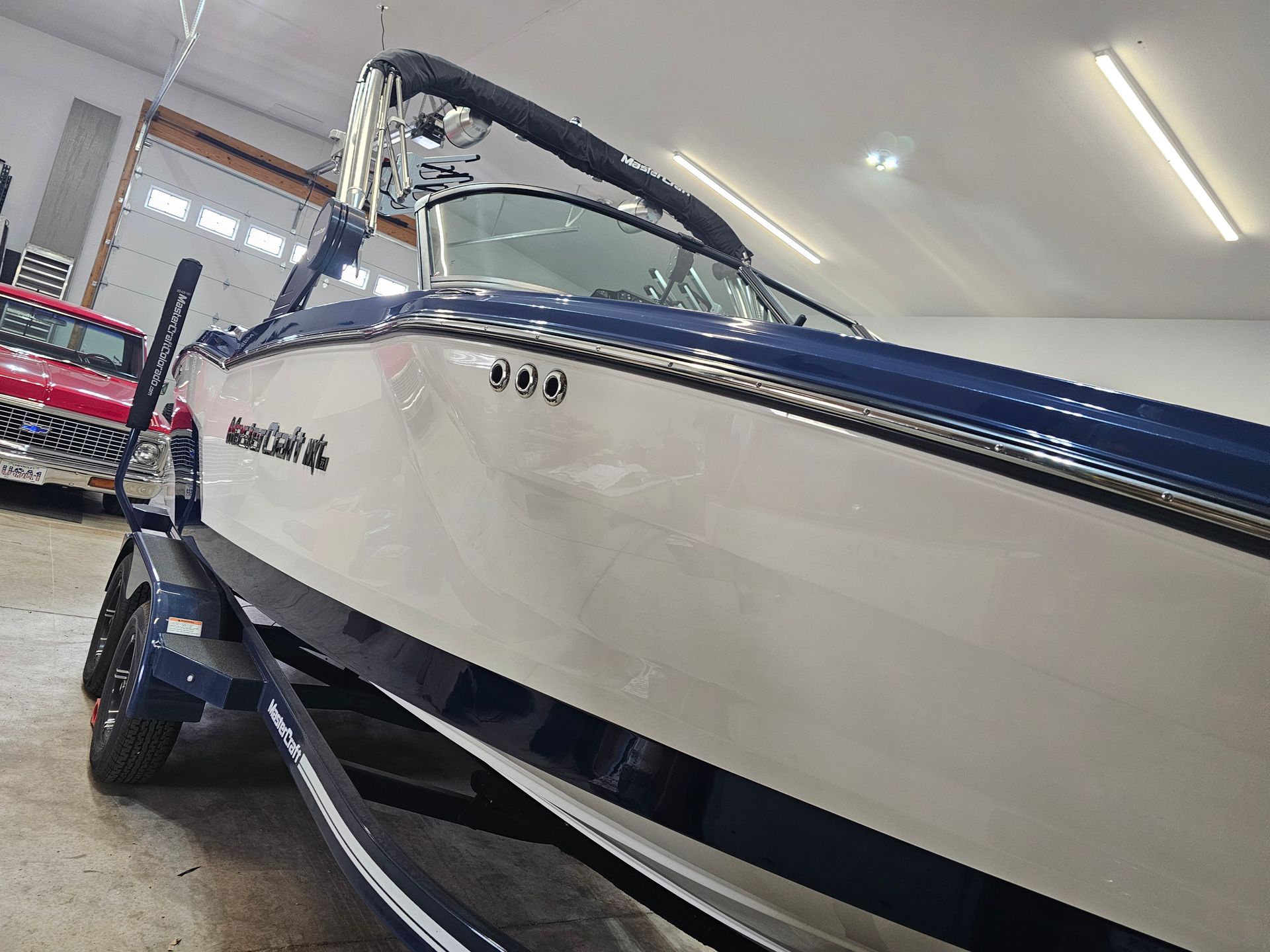 White and navy speedboat on a trailer inside a showroom garage