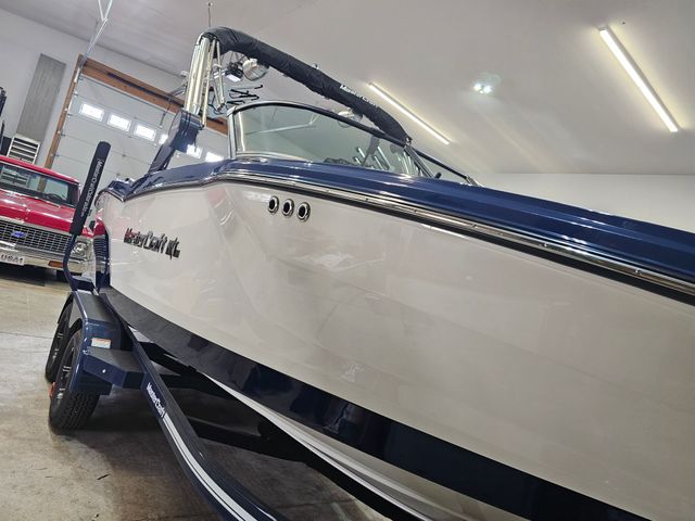 Blue-and-white boat on a trailer inside a garage or showroom, seen from the front side.