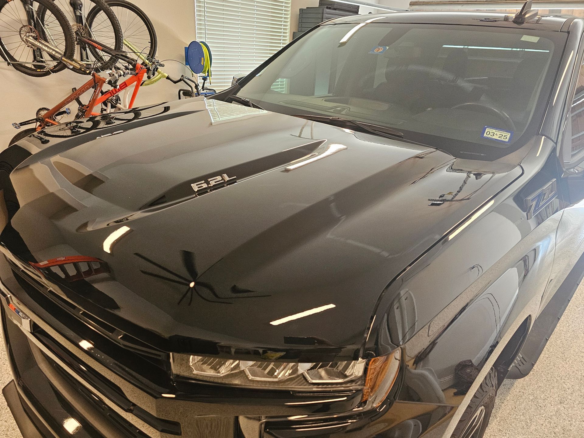 Black pickup truck in a garage with a bicycle rack mounted on the wall behind it