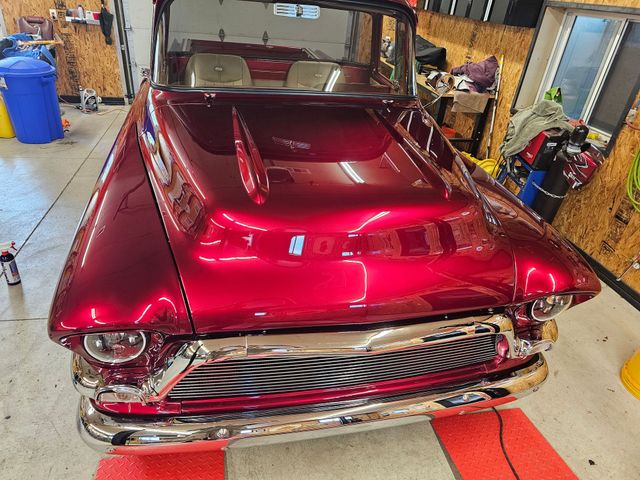 Custom red classic car with chrome grille in a garage workshop