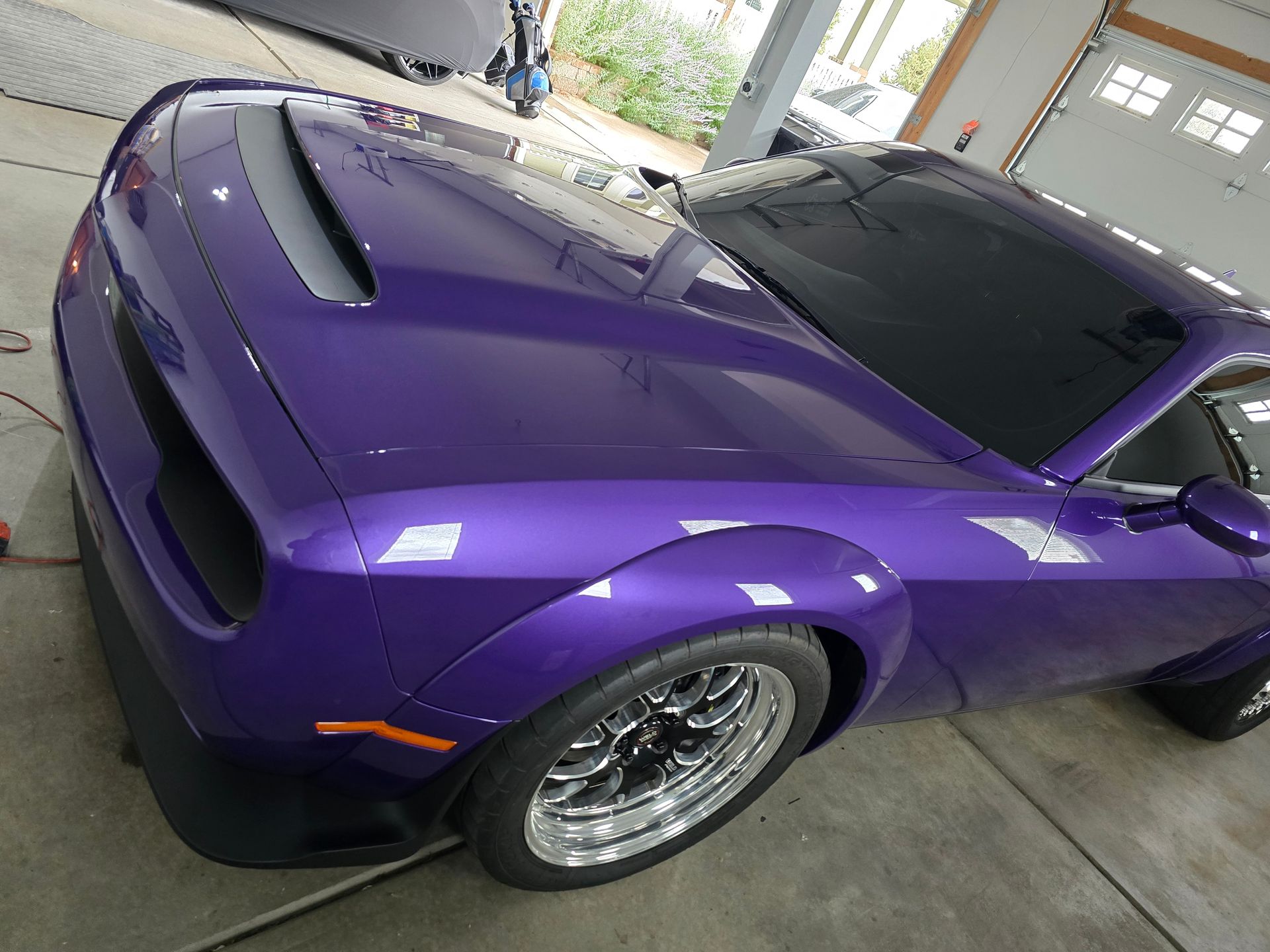 Purple sports car parked in a driveway, front-left view