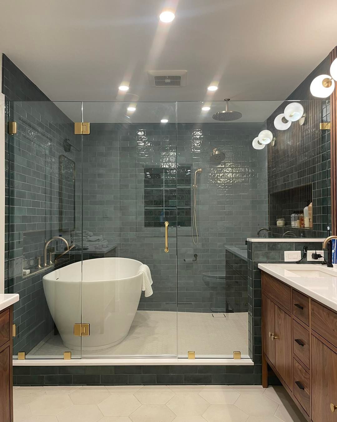 Bathroom with a freestanding white tub, glass shower enclosure, and teal tile walls.