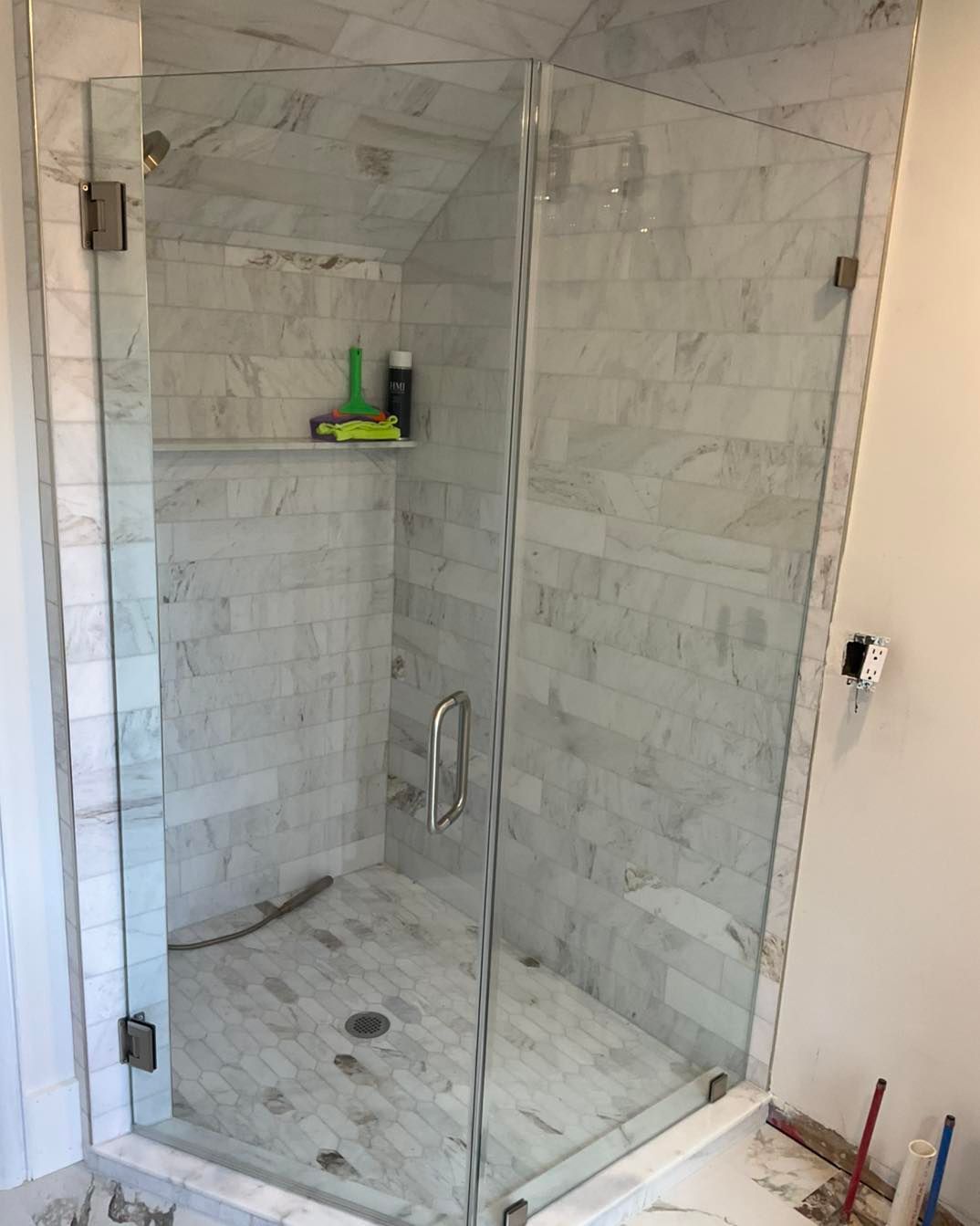 Glass shower enclosure with marble tile walls and floor.