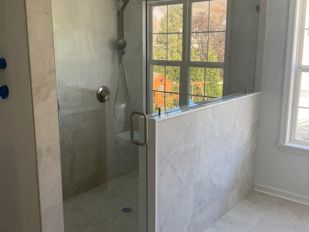Shower with glass doors and a window, light-colored walls and floor.