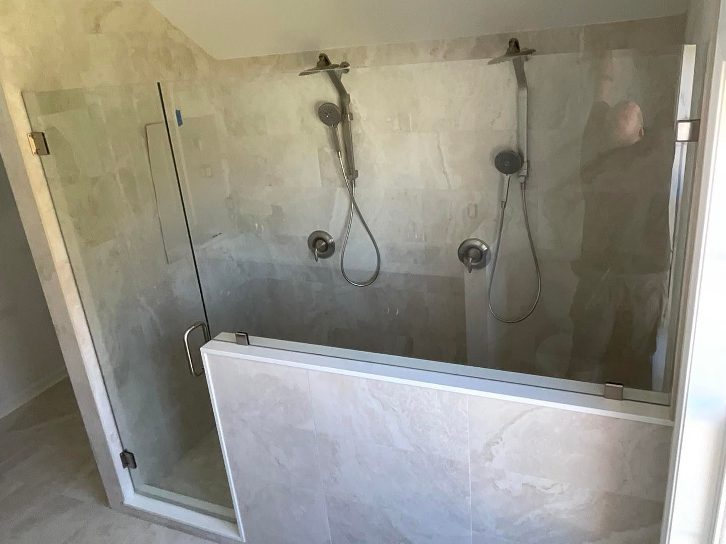 Two-person shower with glass doors, two shower heads, and tiled walls.
