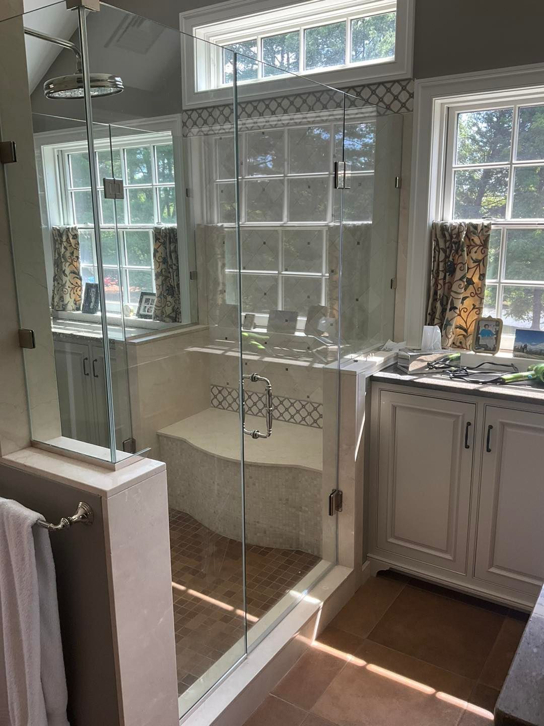 Modern shower stall with glass doors, a built-in bench, and windows above it.