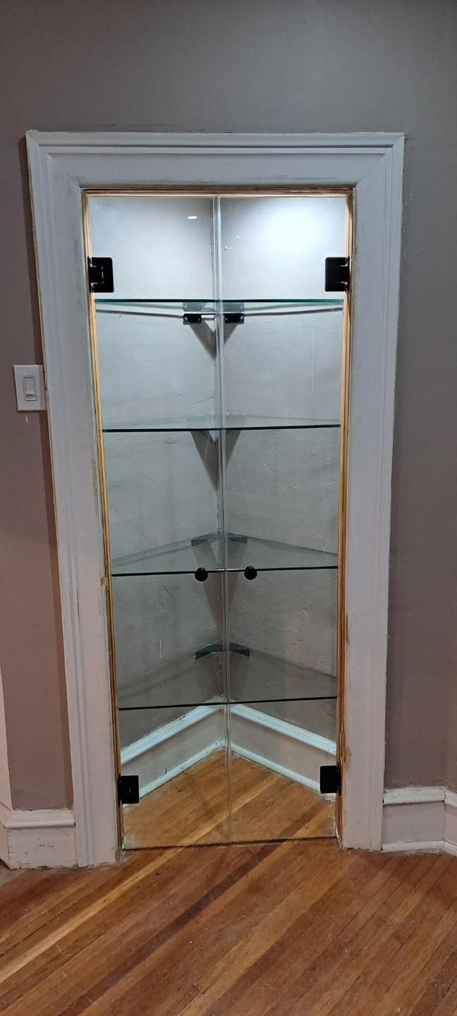 Glass display cabinet built into a wall. White trim surrounds the cabinet, and wooden flooring is in front.