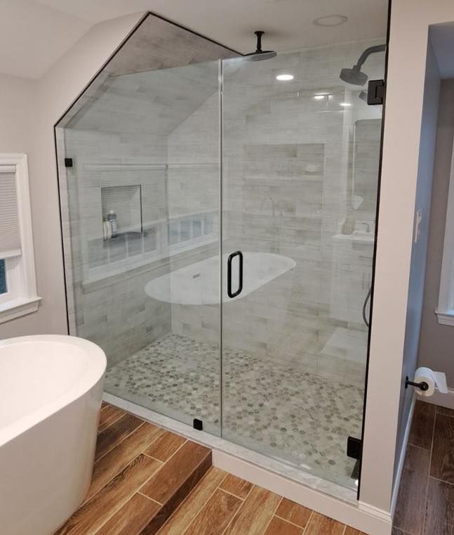 Modern bathroom with a glass shower enclosure, freestanding tub, and pebble shower floor.
