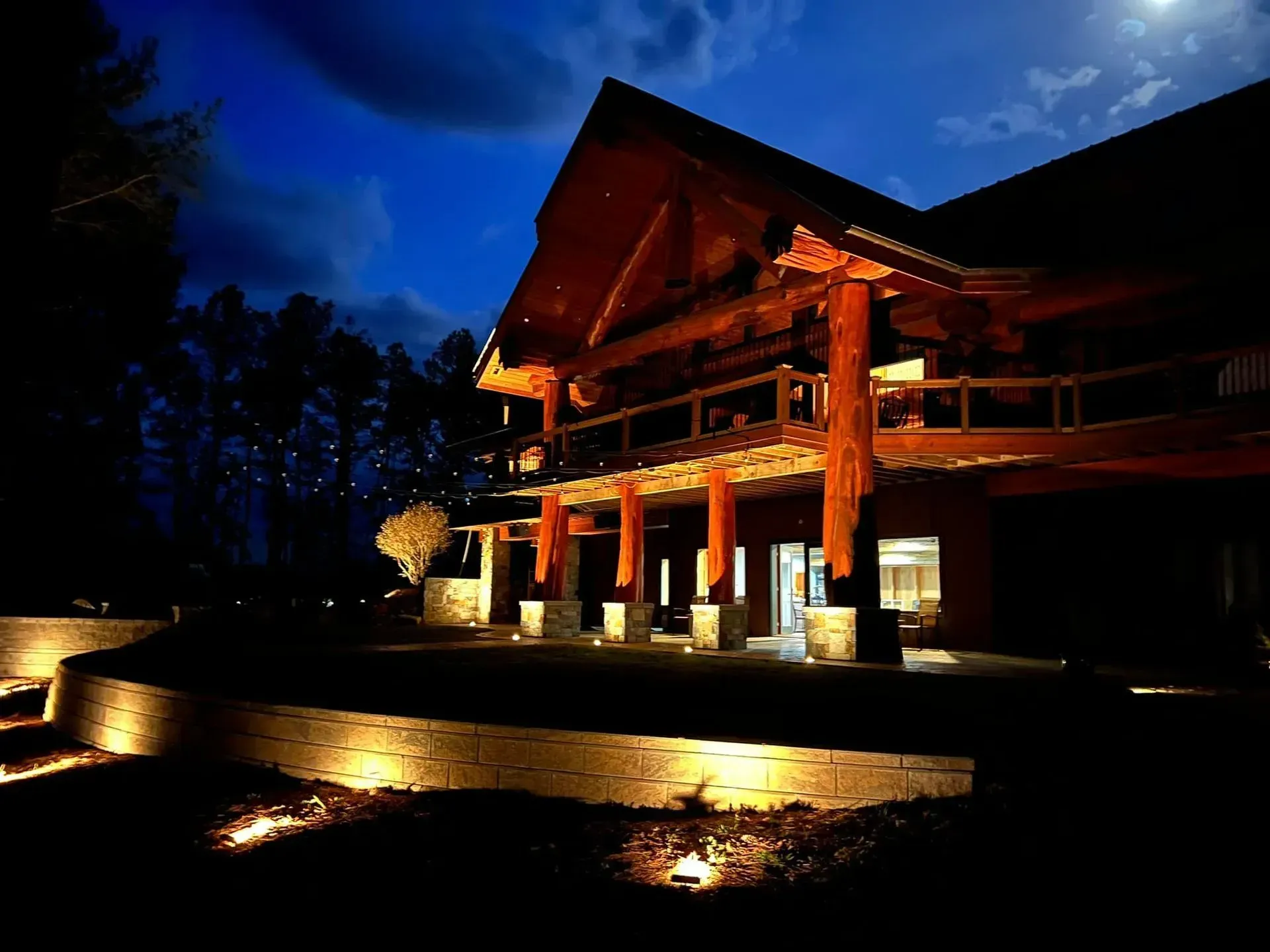 A large wooden house is lit up at night
