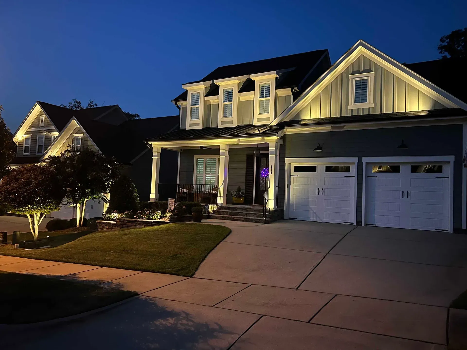 A house is lit up at night in a residential area.