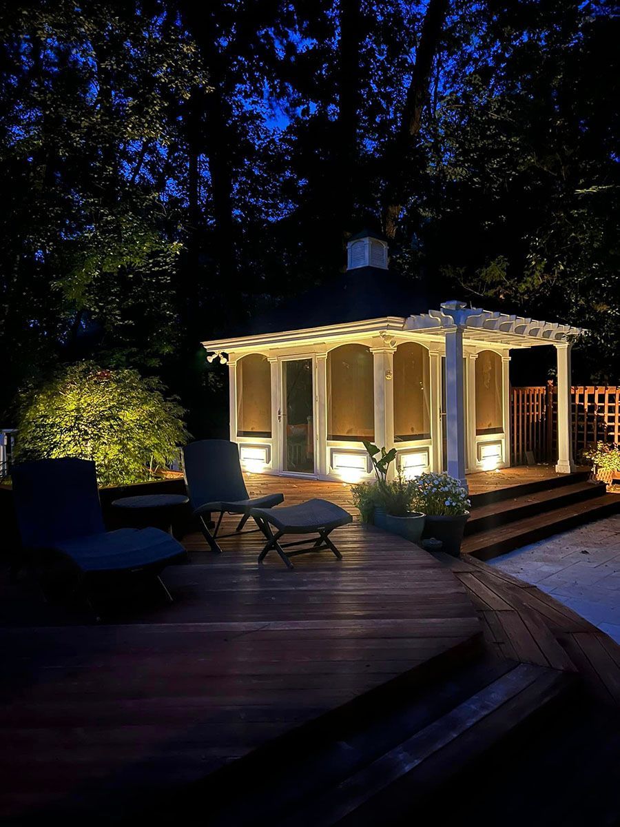 A gazebo is lit up at night in a backyard