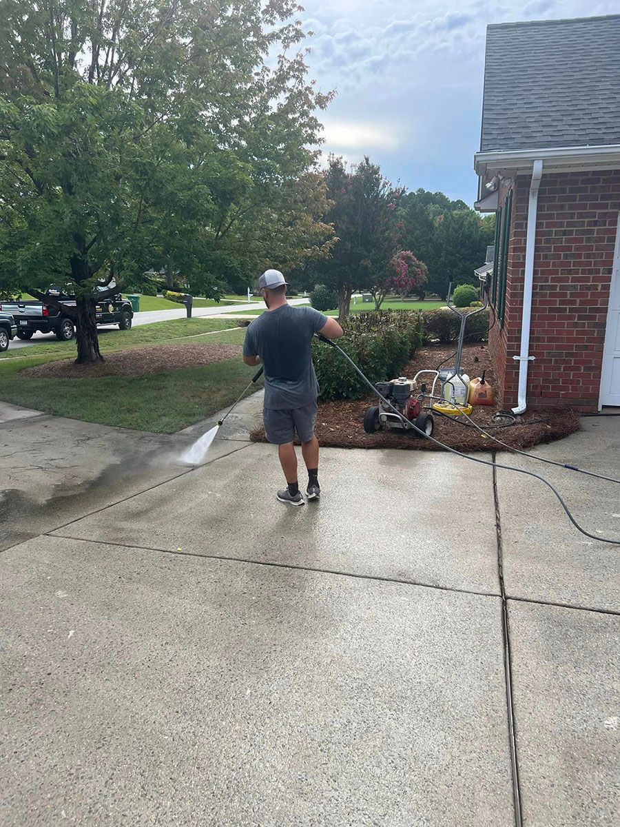 A man is cleaning a driveway with a pressure washer