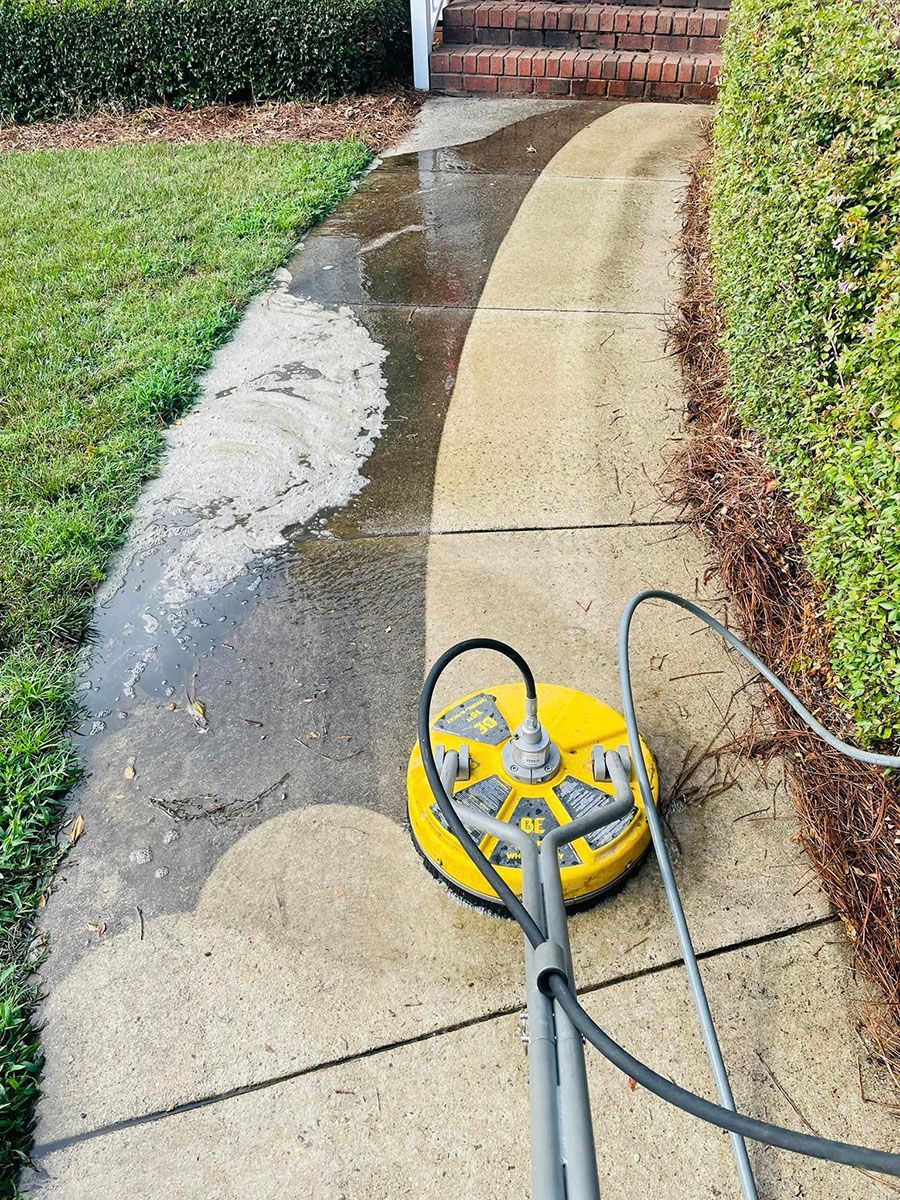 Cleaning a sidewalk next to a lawn