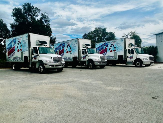 A row of moving trucks are parked in a parking lot
