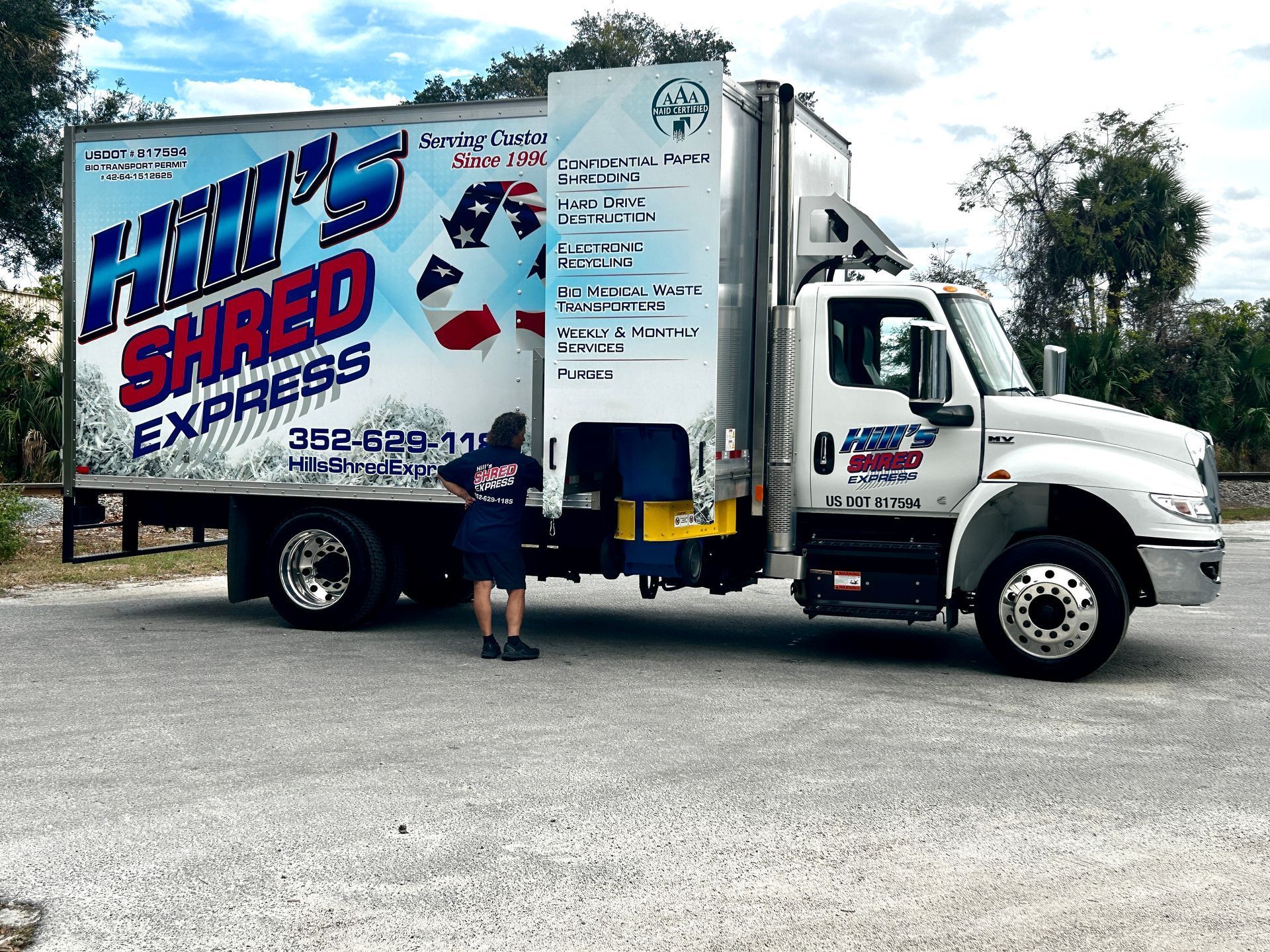 A man is standing next to a hill 's shred express truck