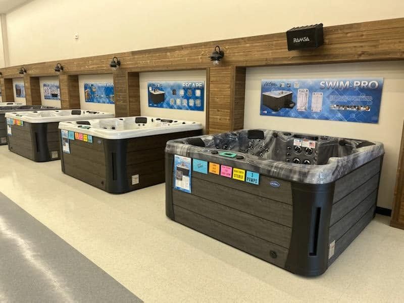 Row of hot tubs in a showroom, with wood-paneled sides and blue wall displays.