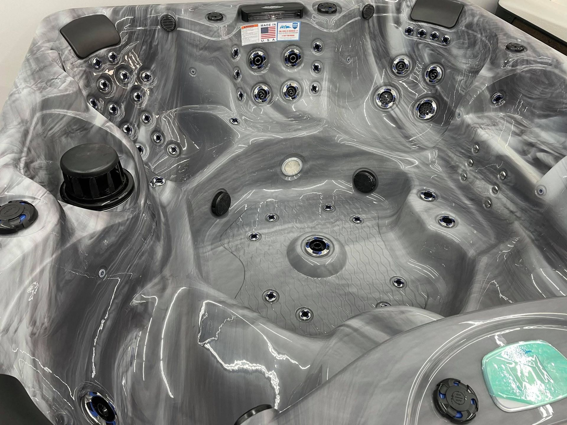 Empty gray hot tub spa with built-in jets, cup holders, and headrests