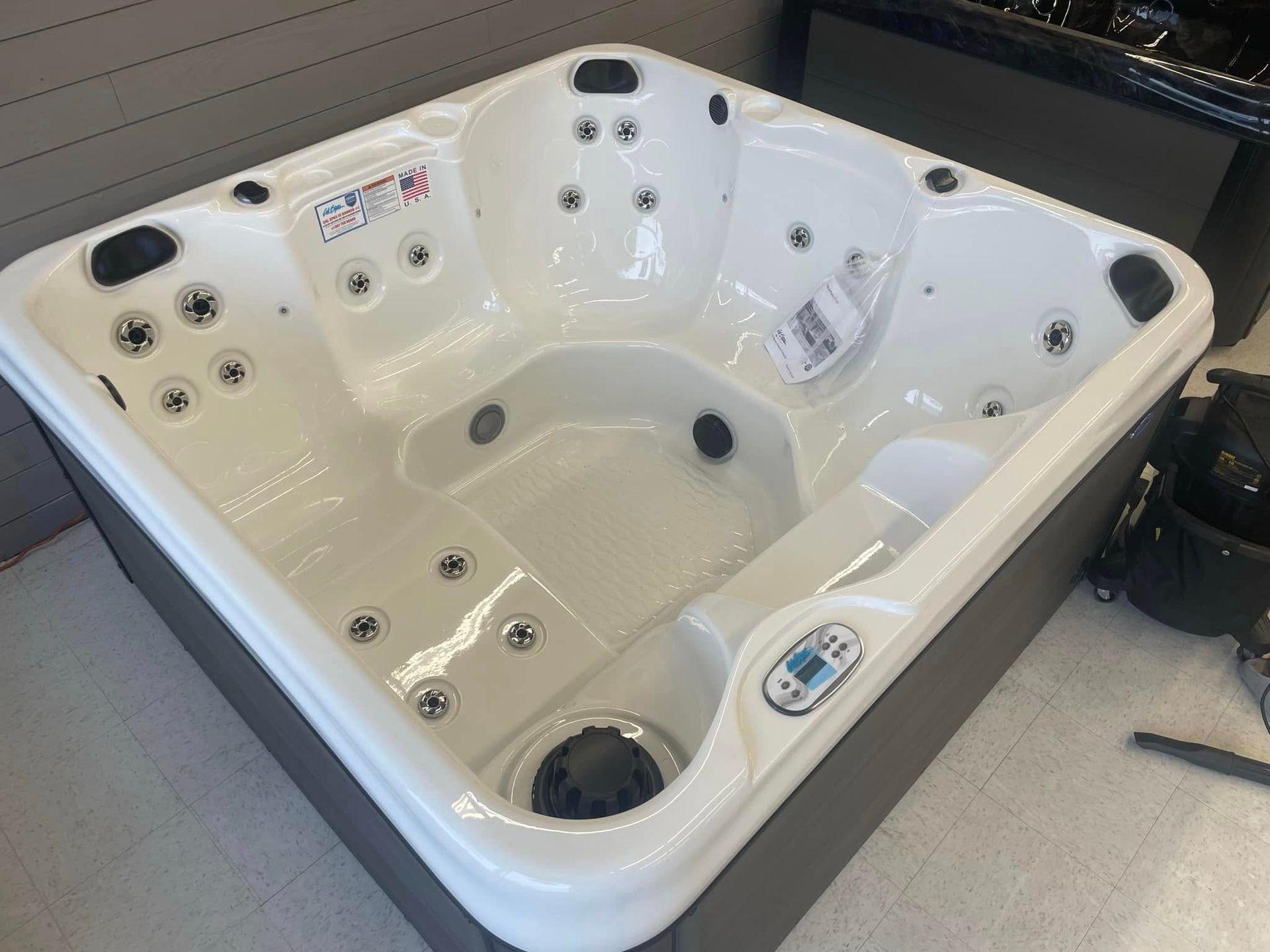 White multi-jet hot tub with built-in seats in a showroom or outdoor display area