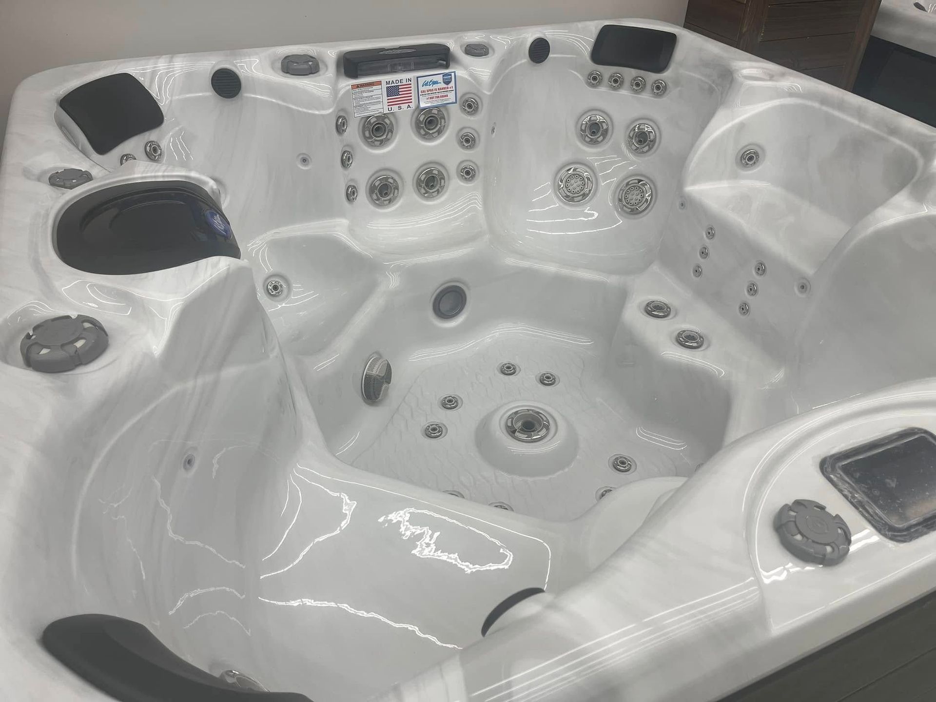 White multi-seat hot tub with built-in jets and control panels, viewed from above
