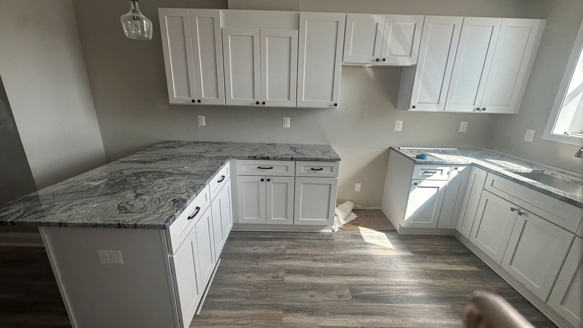 Bright white kitchen with white cabinets and light wood flooring