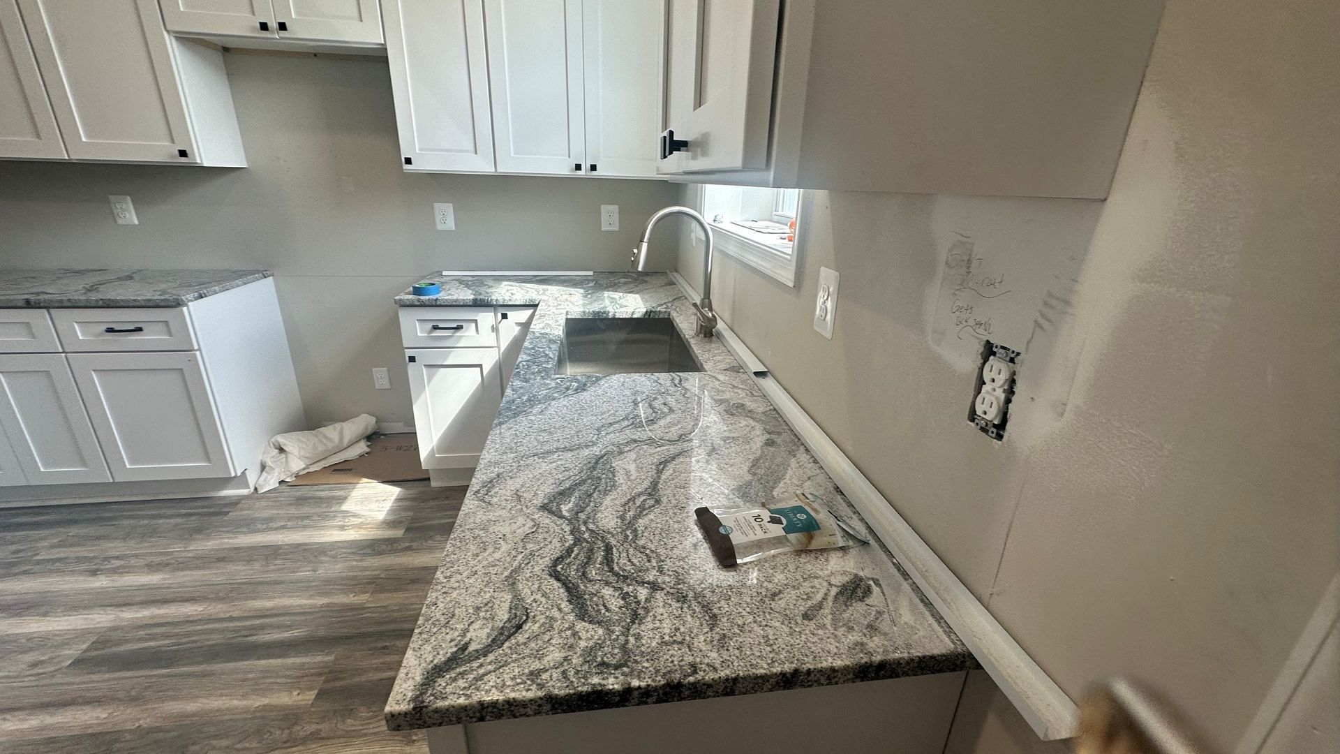 Kitchen with granite counters, white cabinets, and tools on the countertop