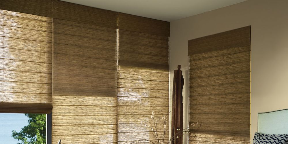View of a room with several brown woven window shades covering the windows. The walls are a neutral beige color.