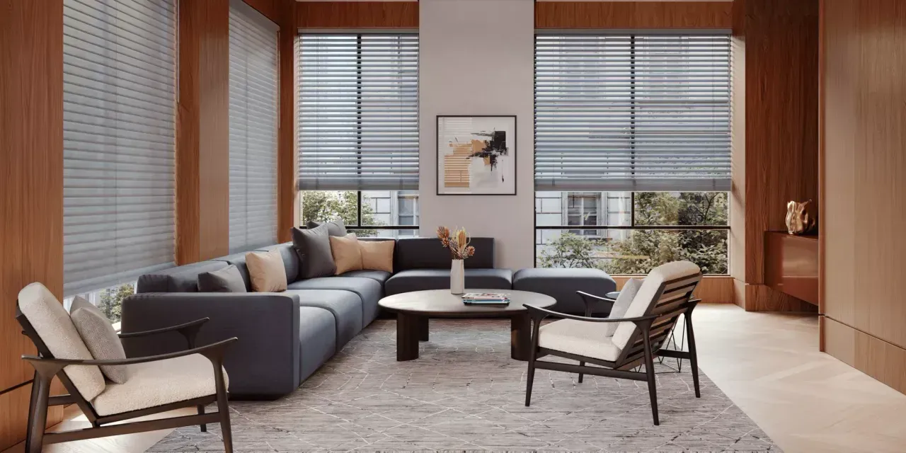 A modern living room with a sectional sofa, two chairs, and a round coffee table. Large windows with blinds provide natural light.