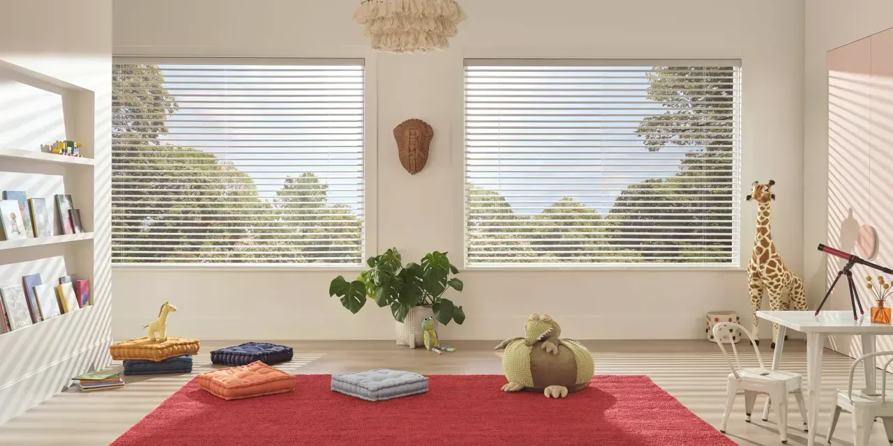 A bright, airy playroom with large windows, a red rug, and various toys, including a giraffe and telescope.