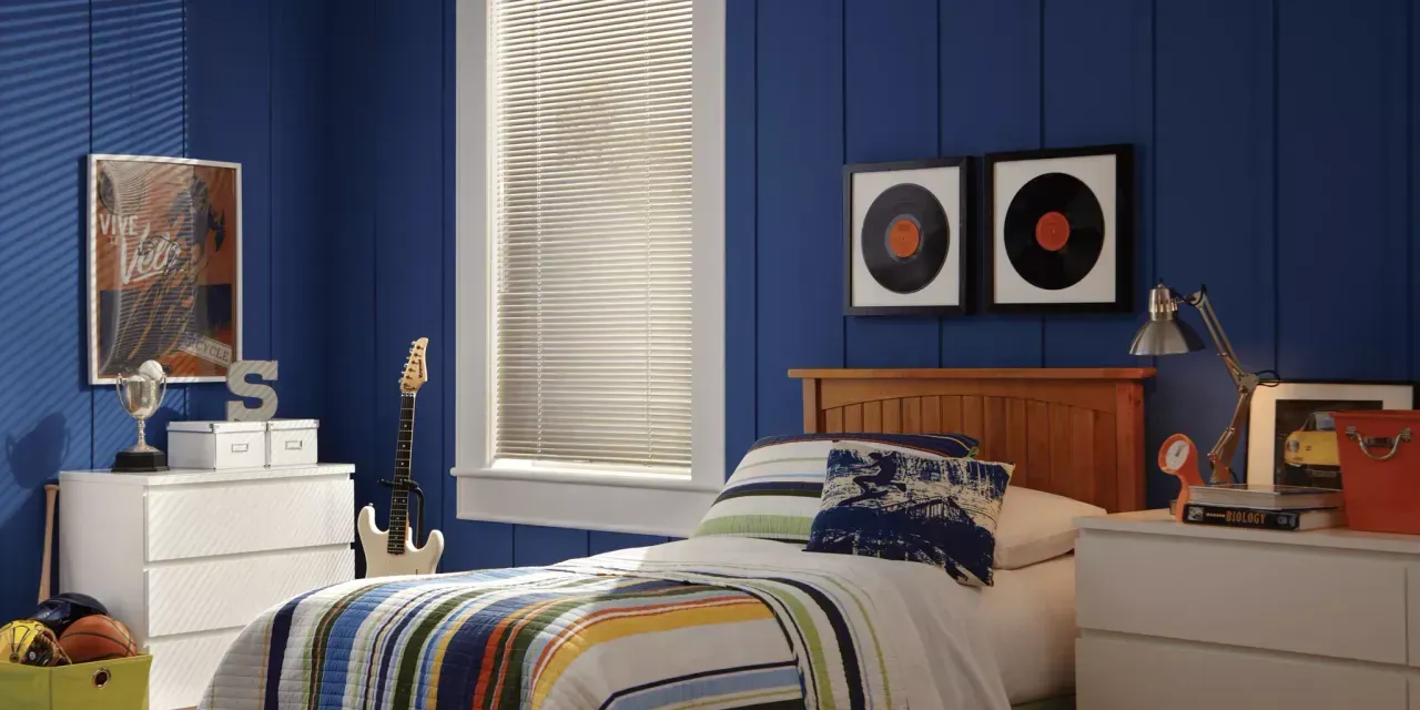 Bedroom with blue paneled walls, a bed, and framed vinyl records. A dresser with art and decor sits on either side of the bed.