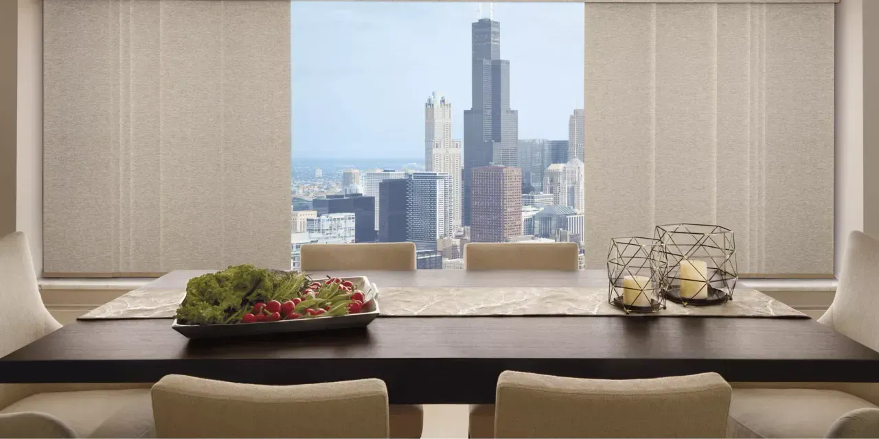 Dining room with a cityscape view through the window. A dark wood table is set with a salad and candle holders.
