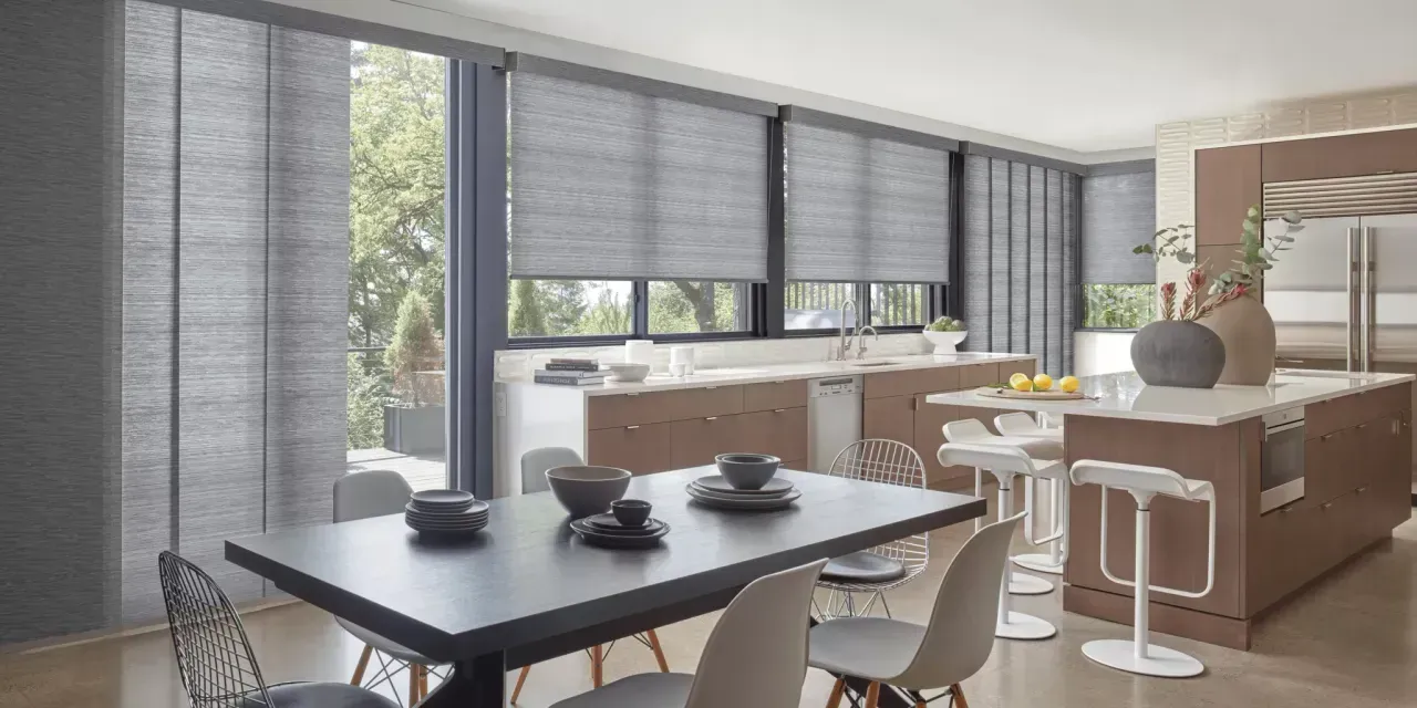Modern kitchen and dining area with gray window shades, a black dining table, and a brown kitchen island with white bar stools.