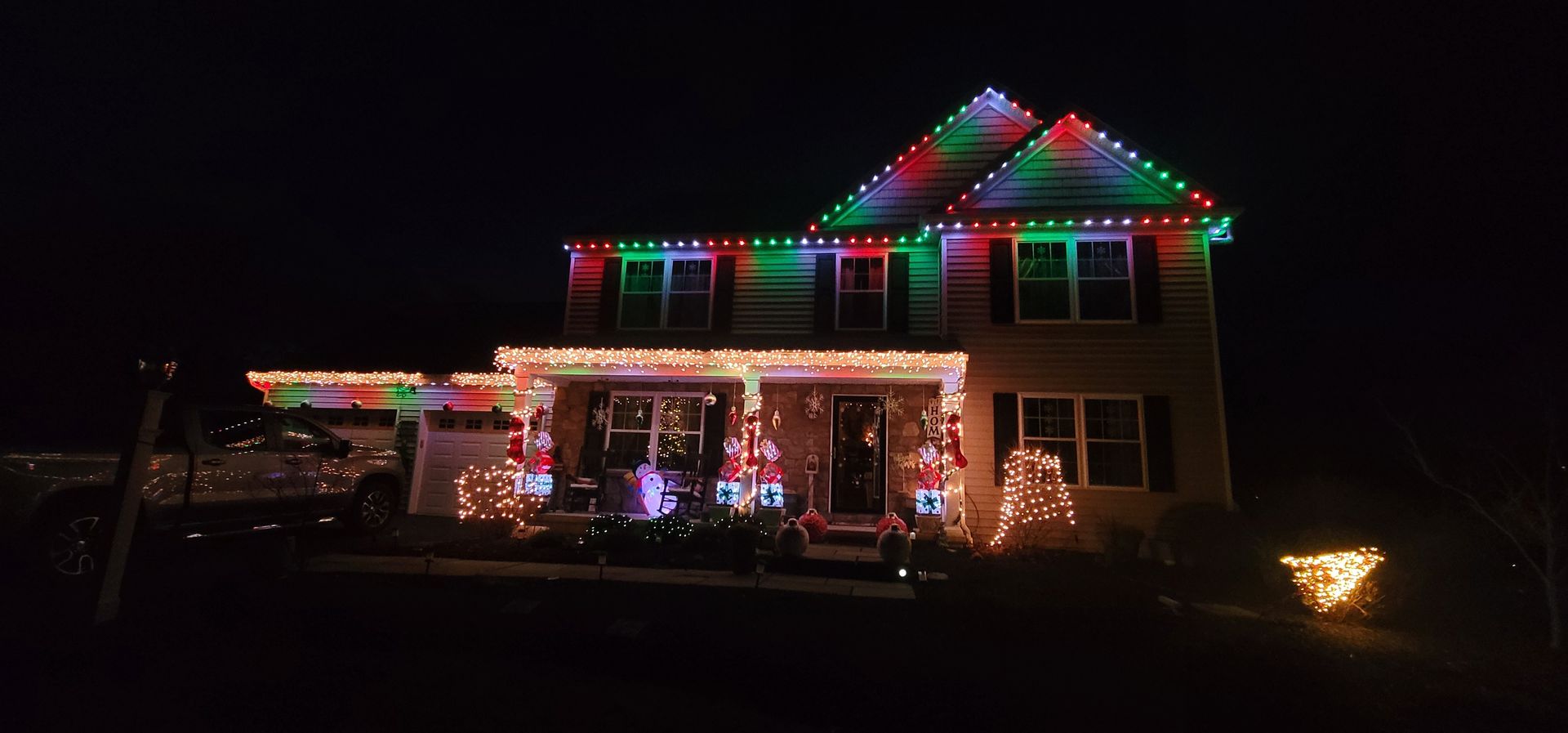 A house decorated for Christmas with colorful lights along the roof and porch.