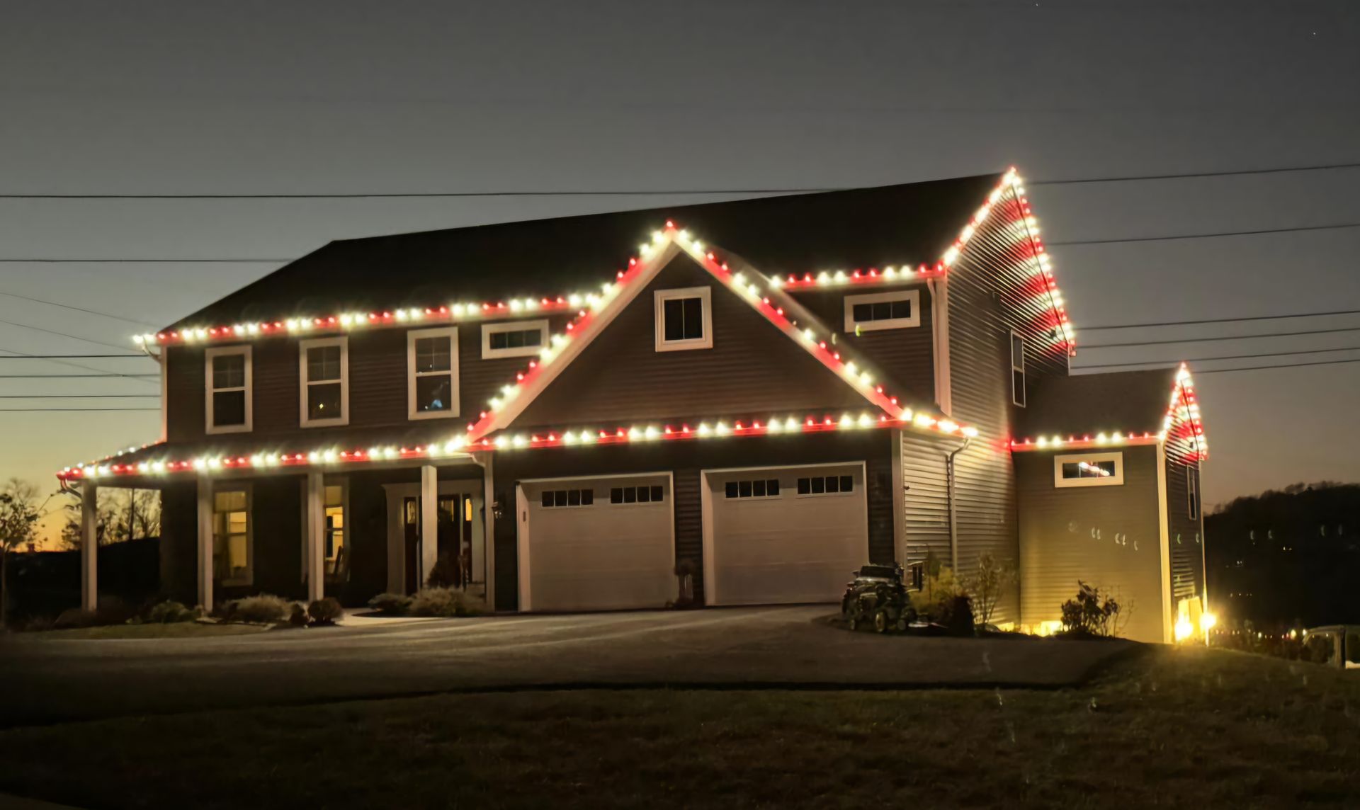 House decorated with white and red Christmas lights at dusk.