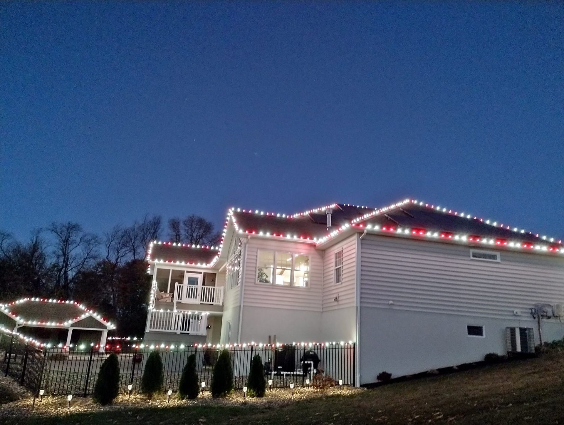 House decorated with red and white Christmas lights against a blue dusk sky.