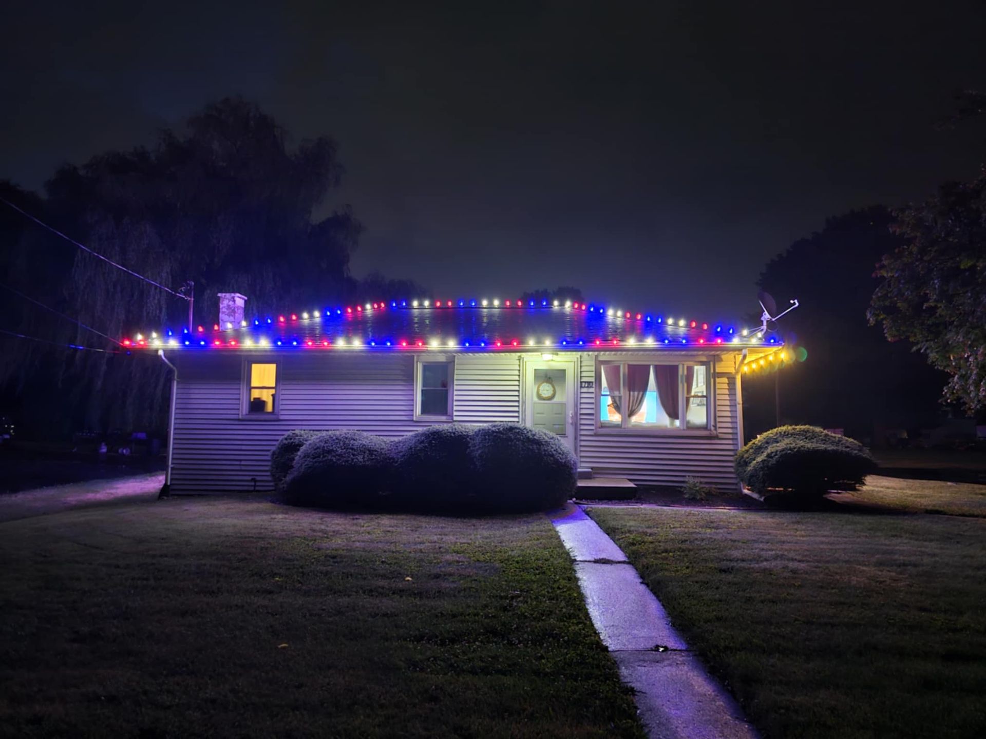 House at night decorated with red, white, and blue lights.