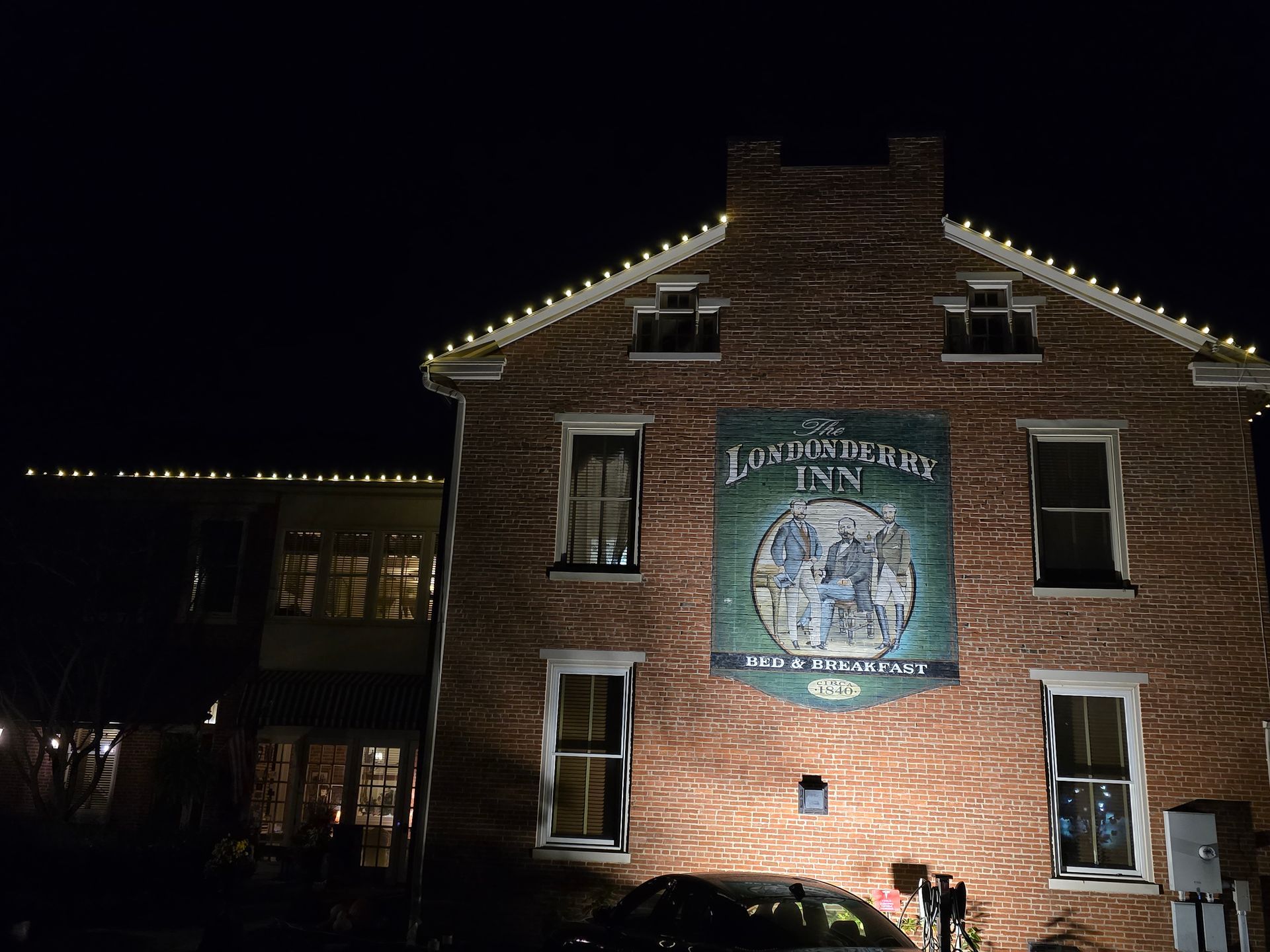 A brick building at night, with a sign for Los Angeles Inn. Illuminated with lights.