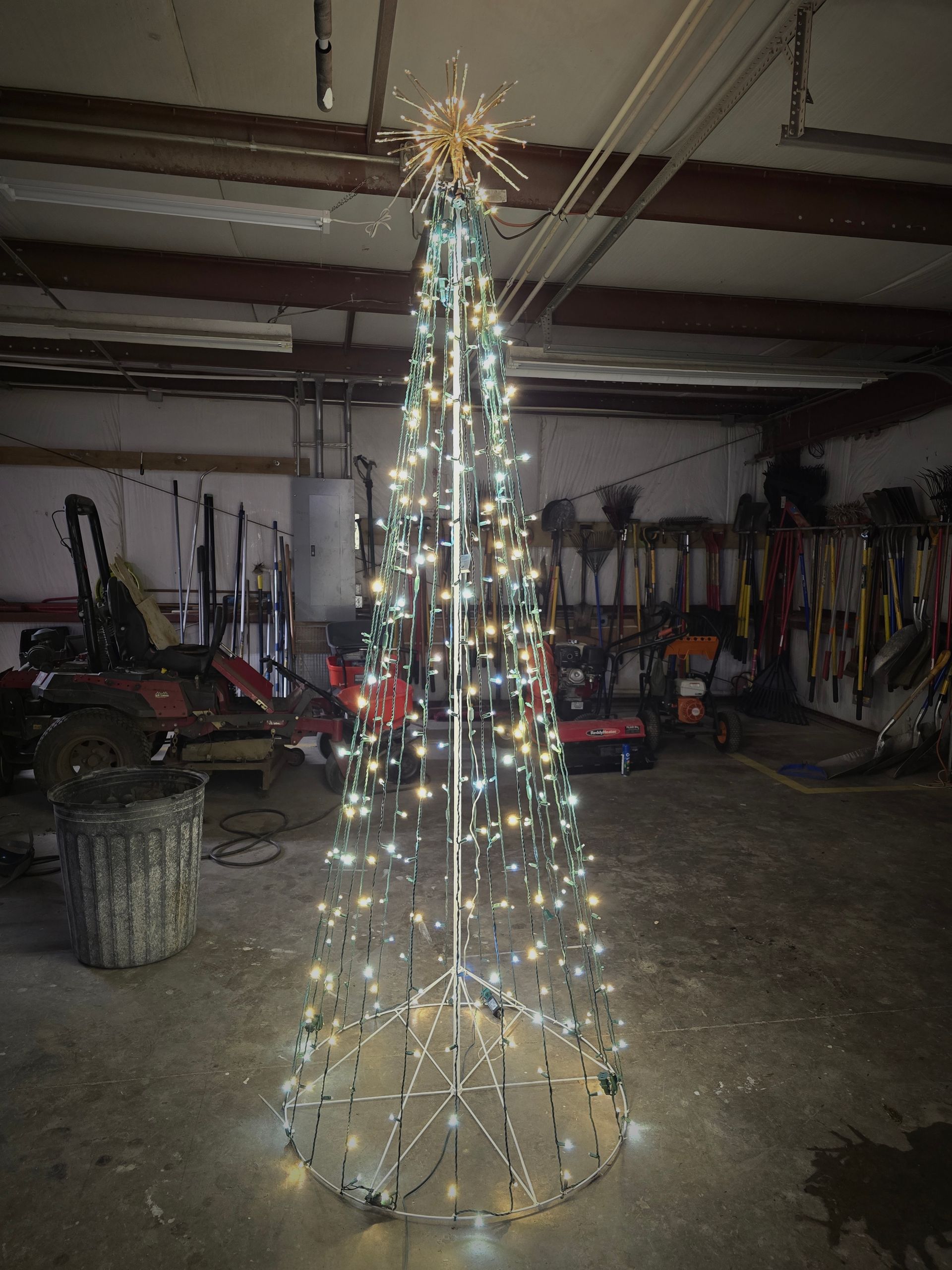 Light-up, cone-shaped Christmas tree with star topper in a garage.
