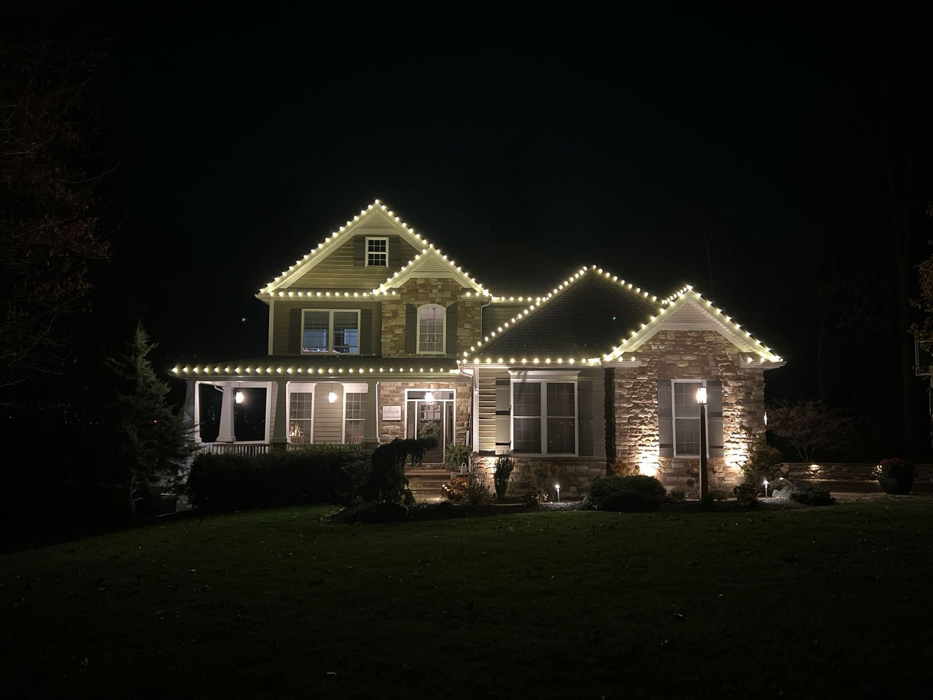 House at night illuminated with white Christmas lights.