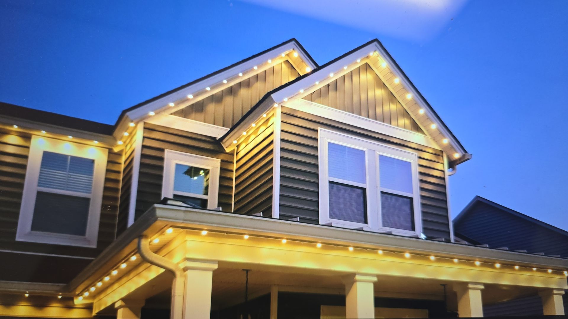 House exterior with warm white string lights outlining roof edges and porch.