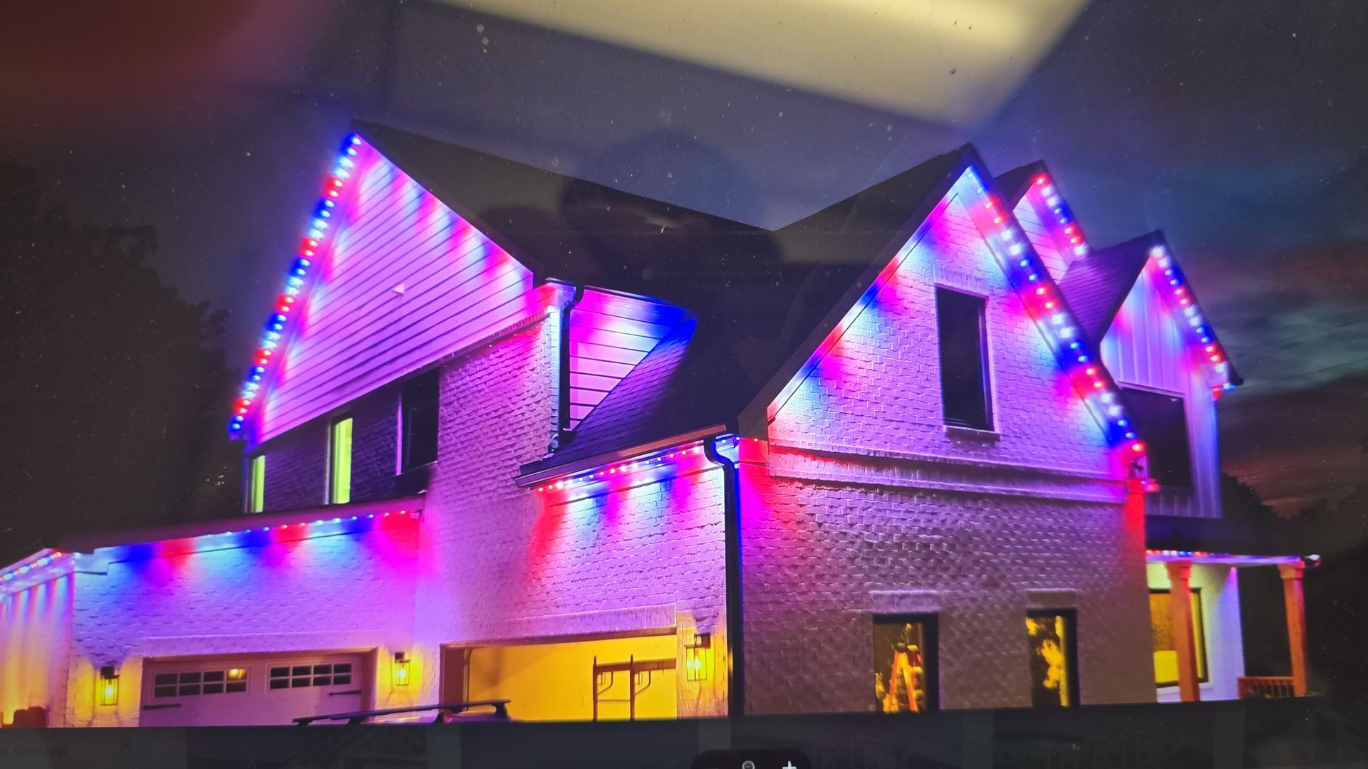 House lit with red, white, and blue Christmas lights against a dark night sky.