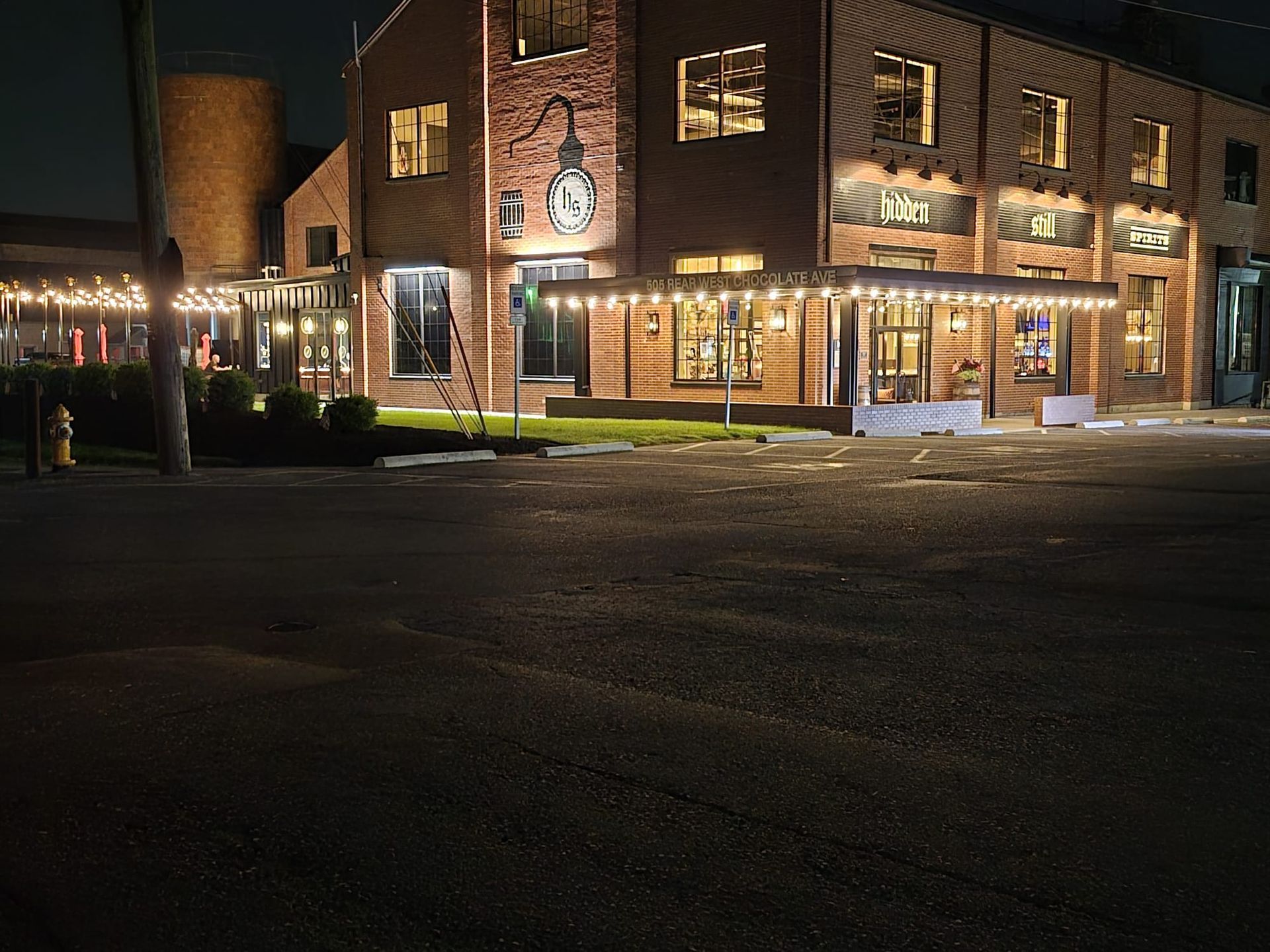 Brick building at night with string lights and a small porch.