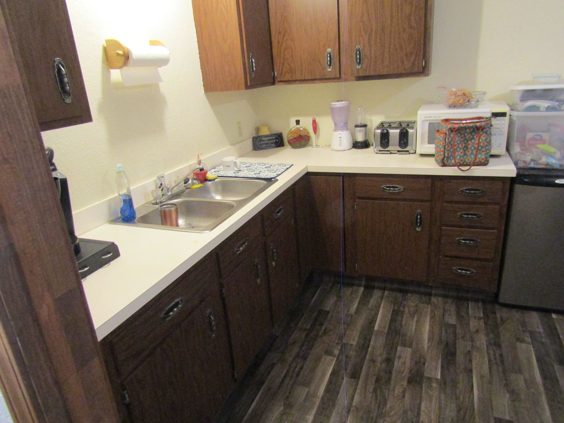 A kitchen with wooden cabinets , a sink , a microwave , and a dishwasher.